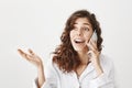 Portrait of excited attractive european adult girl with trendy haircut talking on cellphone while gesturing and looking Royalty Free Stock Photo