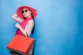 Portrait of an excited beautiful girl wearing dress white T-Shirt, pink hat and sunglasses holding shopping bags isolated over Royalty Free Stock Photo