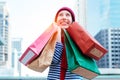 Portrait of an excited beautiful young girl wear shirt and wool hat holding many shopping bags and smile. With copy space. Royalty Free Stock Photo