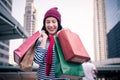 Portrait of an excited beautiful young girl wear shirt and wool hat holding many shopping bags and smile. With copy space. Royalty Free Stock Photo