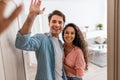 Happy couple inviting people to enter home, giving high five