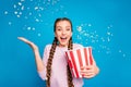 Portrait of excited enthusiastic girl hold box with flying popcorn falling in blowing air wind while watching series tv
