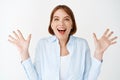 Portrait of excited and enthusiastic woman, spread hands sideways and scream of joy, winning, feeling happy and upbeat