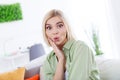 Portrait of excited funny lady wearing khaki shirt touching cheek pouted lips surprisingly reaction when sit indoors on