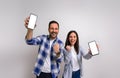 Portrait of excited girlfriend with boyfriend laughing and pumping fists while showing mobile phones. Ecstatic young couple