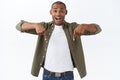 Portrait of excited handsome african-american man talking about big news, great discounts, pointing fingers down, look