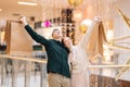 Portrait of excited happy beautiful young couple in love holding shopping bags standing in mall and looking up. Royalty Free Stock Photo