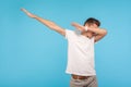 Portrait of excited happy man in white t-shirt showing dab dance, popular internet meme pose