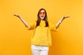 Portrait of excited happy woman in fur sweater, white pants and heart orange glasses spreading hands isolated on bright