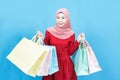 Portrait of excited happy young shopaholic beautiful asian muslim woman  in red traditional dress   posing isolated over blue Royalty Free Stock Photo