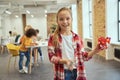 Portrait of excited little girl smiling at camera and showing her diy robot while standing in a classroom during STEM Royalty Free Stock Photo