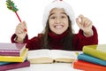 Portrait of excited little girl wearing Santa`s hat and looking up. Surprised little girl learn at the table. Royalty Free Stock Photo