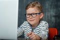 Portrait of excited little kid boy looking at the laptop screen. Child in glasses on the online education. It lessons Royalty Free Stock Photo