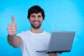 Portrait of an excited man holding laptop computer and celebrating success isolated over blue background Royalty Free Stock Photo