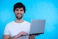 Portrait of an excited man holding laptop computer and celebrating success isolated over blue background Royalty Free Stock Photo