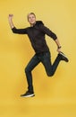 Portrait of an excited man jumping while celebrating success over yellow background Royalty Free Stock Photo