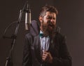 Portrait of excited man in a recording studio. Expressive bearded man in suit with microphone. Karaoke signer, musical