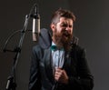 Portrait of excited man in a recording studio. Expressive bearded man in suit with microphone. Karaoke signer, musical