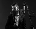 Portrait of excited man in a recording studio. Expressive bearded man in suit with microphone. Karaoke signer, musical