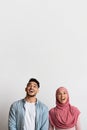 Portrait of excited muslim man and woman looking up with opened mouth