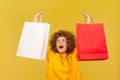 Excited overjoyed woman with Afro hairstyle, raised arms with shopping bags, yelling happily.