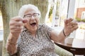 Portrait Of Excited Senior Woman Sitting In Chair In Lounge Of Retirement Home Royalty Free Stock Photo