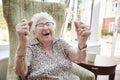 Portrait Of Excited Senior Woman Sitting In Chair In Lounge Of Retirement Home Royalty Free Stock Photo