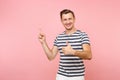 Portrait excited smiling young man wearing striped t-shirt pointing index finger aside on copy space isolated on Royalty Free Stock Photo