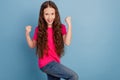 Portrait of excited winner little lady raise fists champion achievement on blue background