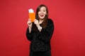 Portrait of excited woman in black fur sweater holding passport, boarding pass ticket isolated on bright red wall Royalty Free Stock Photo