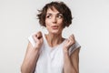 Portrait of excited woman with short brown hair in basic t-shirt rejoicing and clenching fists Royalty Free Stock Photo