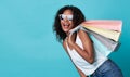 Portrait of an excited young african woman hand holding shopping bag isolated over blue background Royalty Free Stock Photo