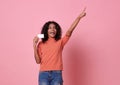 Portrait of an excited young african woman hand point at copy space isolated over pink background Royalty Free Stock Photo