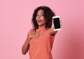 Portrait of a excited young african woman showing at blank screen mobile phone isolated over pink background Royalty Free Stock Photo