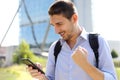 Portrait of excited young business man checking good news on smartphone. University student celebrating with mobile phone in his Royalty Free Stock Photo