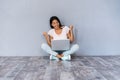 Portrait of excited young casual girl celebrating success while sitting with laptop computer isolated over gray Royalty Free Stock Photo