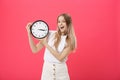 Portrait of an excited young girl dressed in white t-shirt pointing at alarm clock and looking at camera over Royalty Free Stock Photo