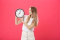 Portrait of an excited young girl dressed in white t-shirt pointing at alarm clock and looking at camera isolated over Royalty Free Stock Photo