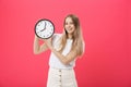 Portrait of an excited young girl dressed in white t-shirt pointing at alarm clock and looking at camera isolated over Royalty Free Stock Photo