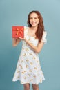 Portrait of an excited young girl holding present box isolated over blue background Royalty Free Stock Photo