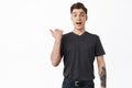 Portrait of excited young man, handsome guy pointing finger left and smiling amazed, tell big news, makes announcement Royalty Free Stock Photo