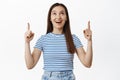Portrait of excited young woman, looking happy up, pointing fingers at sale banner, showing mockup, empty space for Royalty Free Stock Photo