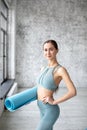 Portrait of exercise fitness woman ready for workout, standing and holding blue yoga mat in sport club studio Royalty Free Stock Photo