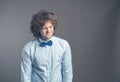 Portrait of exhausted sad guy with shaggy hair standing and looking down with apathy. Isolated on grey background wearing blue