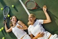 Portrait of Exhausted women lying on tennis court after playing