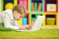 Portrait of exited boy using laptop while lying on floor