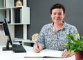 Portrait of an experienced and determined brunette with a short haircut sitting at a desk in a modern office