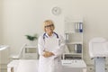 Portrait of experienced senior doctor looking at camera standing in hospital office