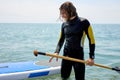 Portrait of experienced surfer with SUP board on beach. Young man with stand up paddleboard