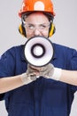 Portrait of Expressive Caucasian Female With Loudspeaker Horn Shouting In Hardhat. Equipped with Coverall